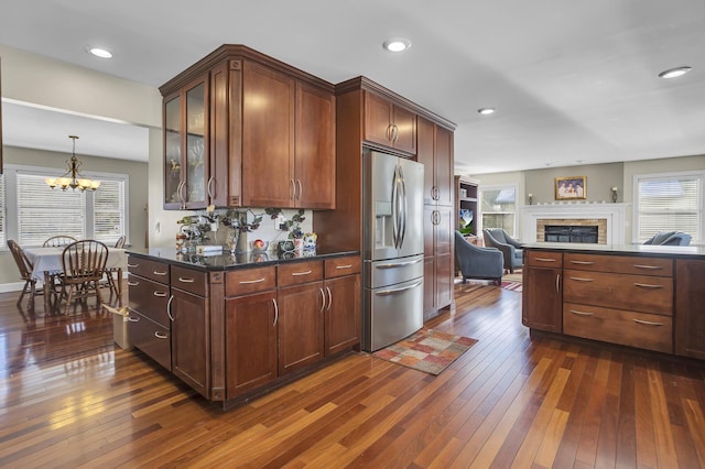 kitchen featuring a fireplace, open floor plan, dark wood finished floors, and stainless steel fridge with ice dispenser