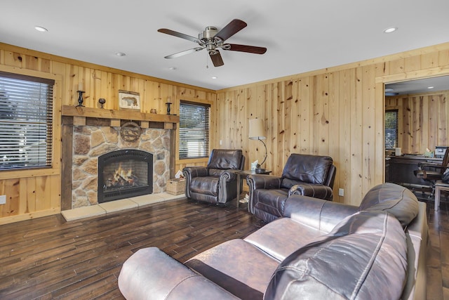 living area with wood walls, a stone fireplace, and hardwood / wood-style flooring