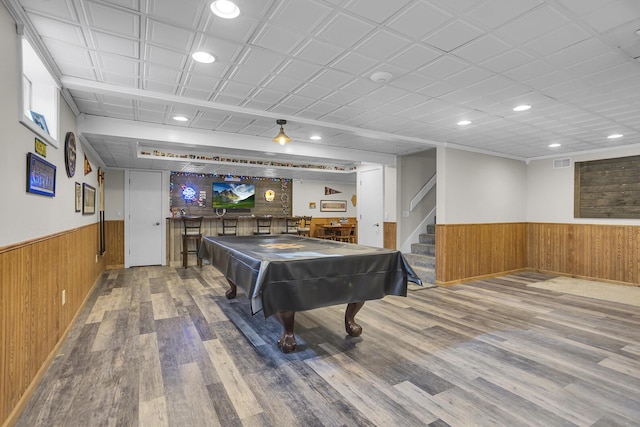 recreation room with a wainscoted wall, a bar, wood walls, and visible vents