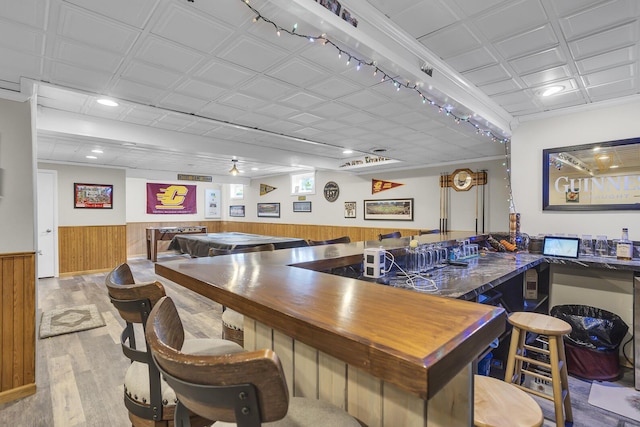 interior space featuring wooden walls, wainscoting, wood finished floors, wet bar, and recessed lighting