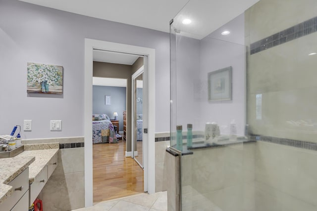 ensuite bathroom featuring tile walls, ensuite bathroom, an enclosed shower, vanity, and tile patterned floors