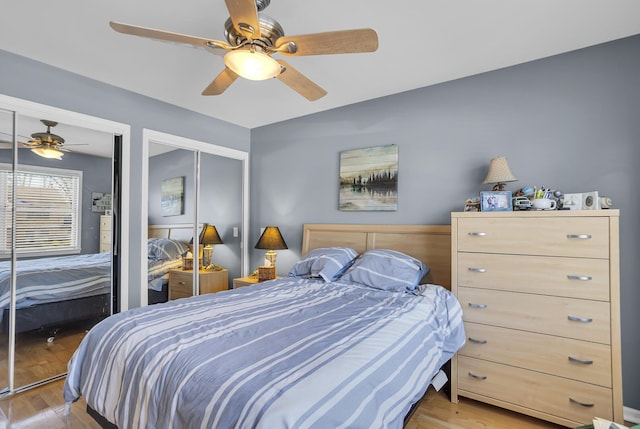 bedroom featuring wood finished floors, ceiling fan, and two closets