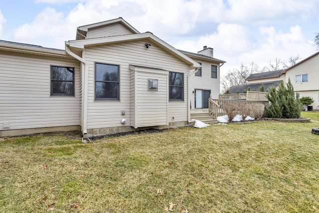 rear view of property featuring a lawn, a chimney, and a wooden deck