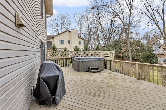 wooden deck with area for grilling and a hot tub