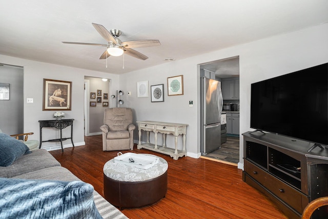 living area featuring wood finished floors, a ceiling fan, and baseboards