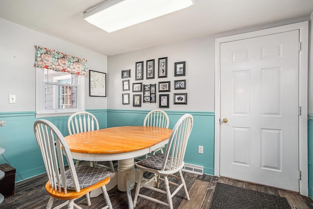 dining space featuring a wainscoted wall and wood finished floors