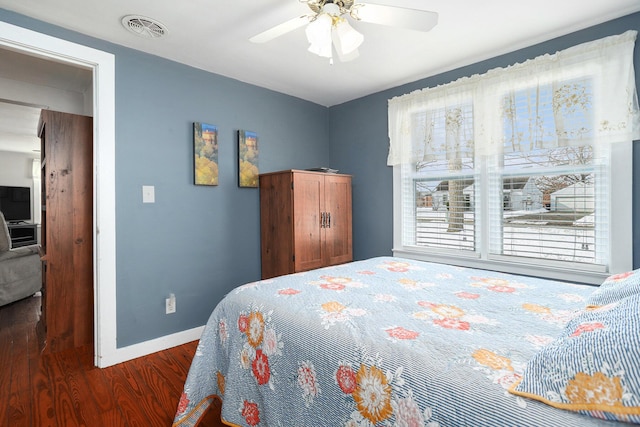 bedroom with dark wood-style floors, baseboards, visible vents, and a ceiling fan