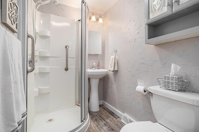 bathroom featuring visible vents, a textured wall, toilet, a stall shower, and wood finished floors