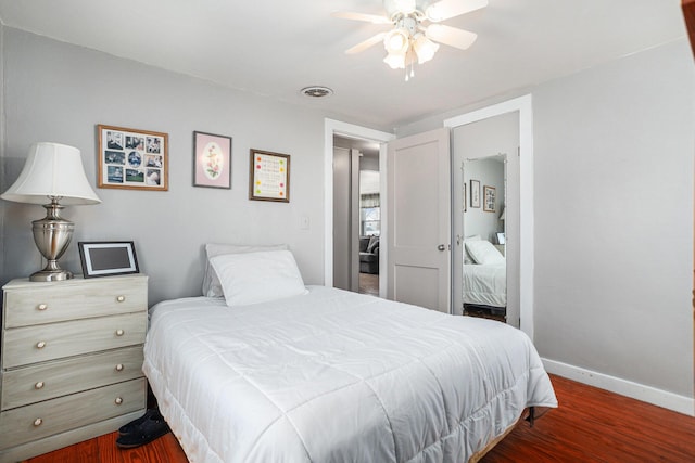 bedroom featuring ceiling fan, wood finished floors, visible vents, and baseboards