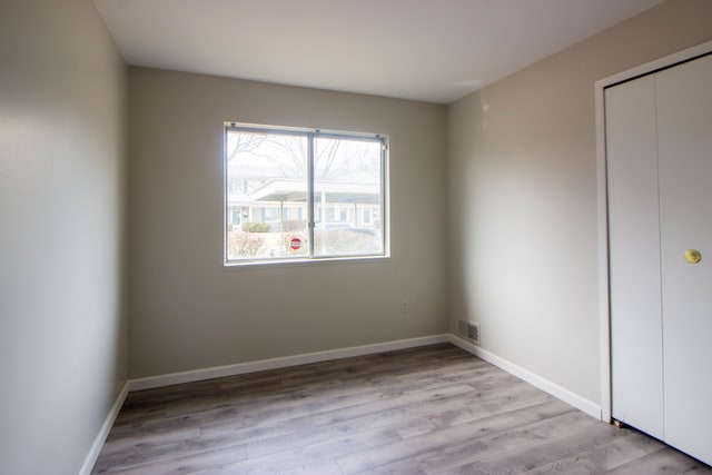 unfurnished bedroom featuring light wood-style floors, visible vents, baseboards, and a closet