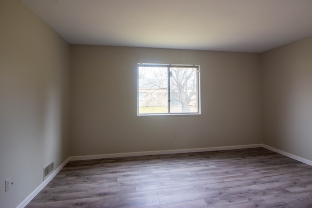 unfurnished room featuring visible vents, baseboards, and wood finished floors