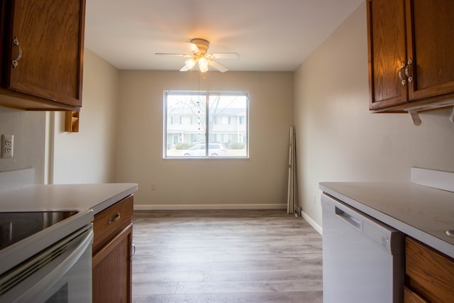 kitchen featuring brown cabinets, light countertops, light wood-type flooring, white appliances, and baseboards