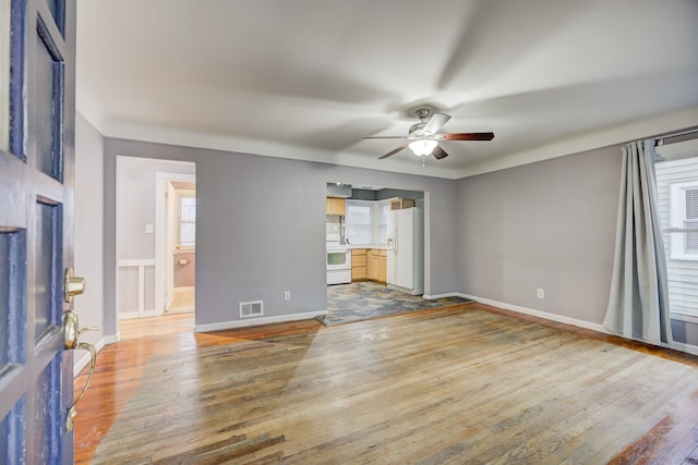 interior space with wood-type flooring, visible vents, ceiling fan, and baseboards