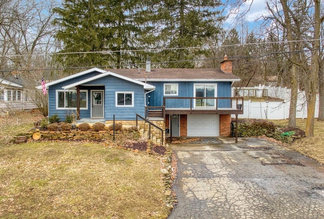 view of front of home with aphalt driveway, an attached garage, fence, a front lawn, and a chimney