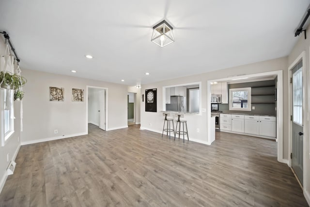 unfurnished living room featuring recessed lighting, visible vents, baseboards, and wood finished floors