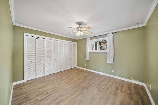 unfurnished bedroom with visible vents, crown molding, baseboards, and wood finished floors