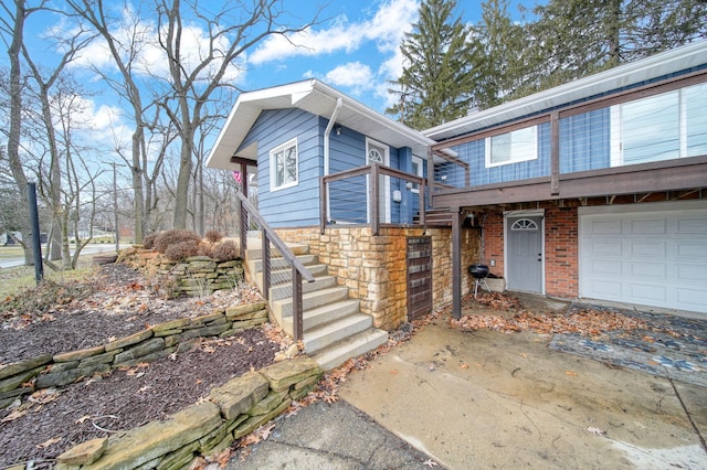 view of front facade with brick siding, a garage, stone siding, driveway, and stairs