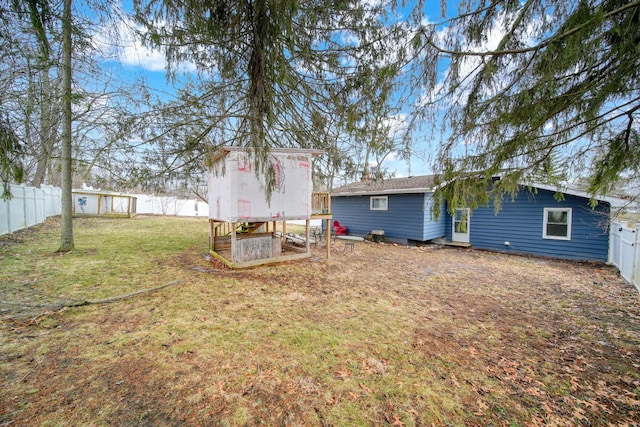 rear view of property with an outbuilding, a lawn, and a fenced backyard