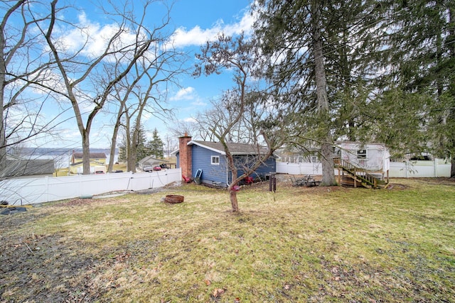 view of yard with an outbuilding, a fenced backyard, and an outdoor fire pit