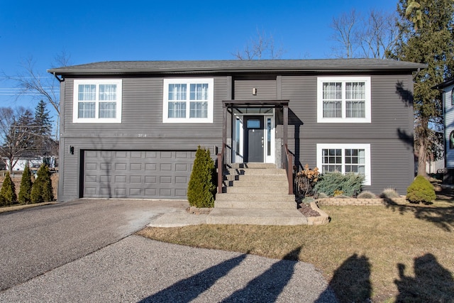 raised ranch with aphalt driveway, a front yard, and an attached garage