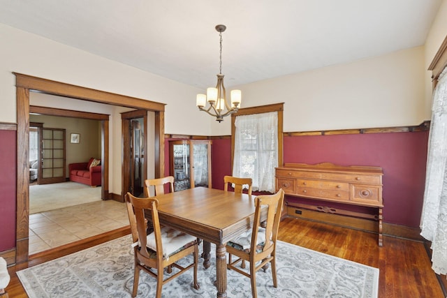 dining space with a notable chandelier, baseboards, and wood finished floors