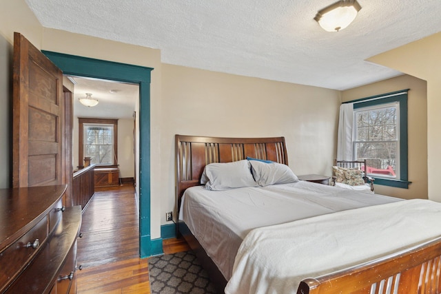 bedroom with a textured ceiling, wood-type flooring, and baseboards