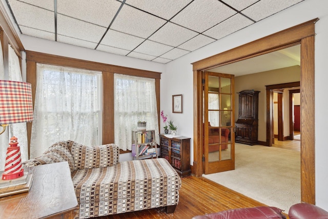 living area featuring a paneled ceiling and wood finished floors