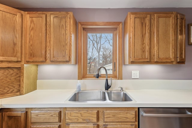 kitchen with a sink, brown cabinetry, light countertops, and stainless steel dishwasher