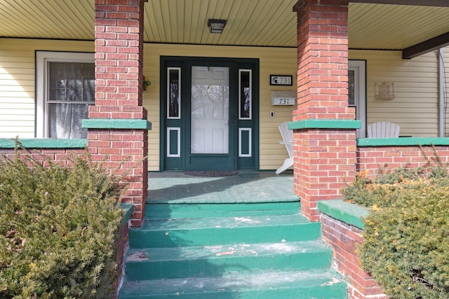 view of exterior entry with covered porch and brick siding