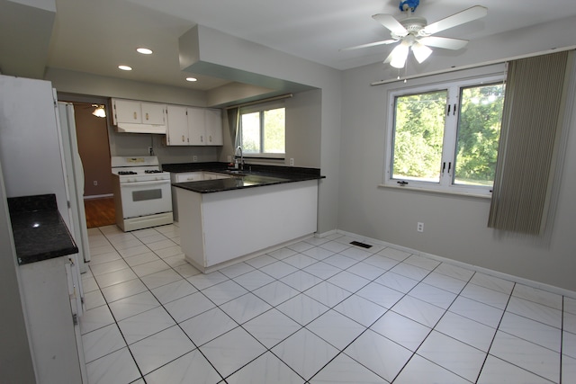 kitchen featuring white gas range, dark countertops, a sink, a peninsula, and under cabinet range hood