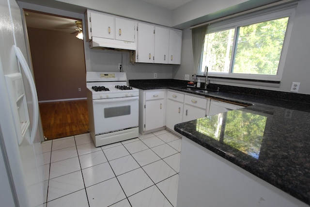 kitchen featuring light tile patterned floors, white cabinets, a sink, white appliances, and under cabinet range hood