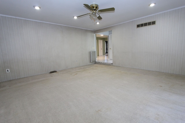 empty room with ceiling fan, carpet flooring, visible vents, and crown molding