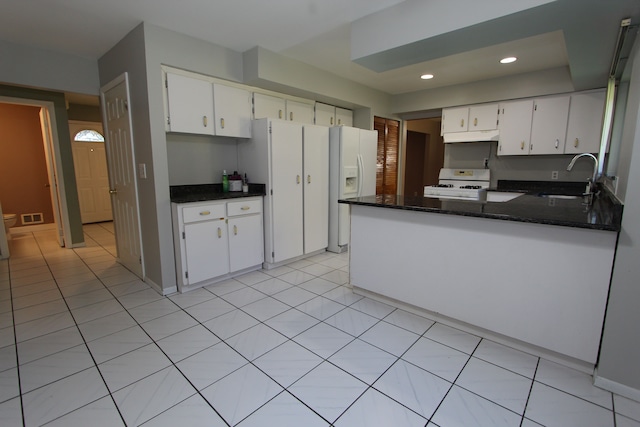 kitchen with a peninsula, white appliances, white cabinetry, and a sink