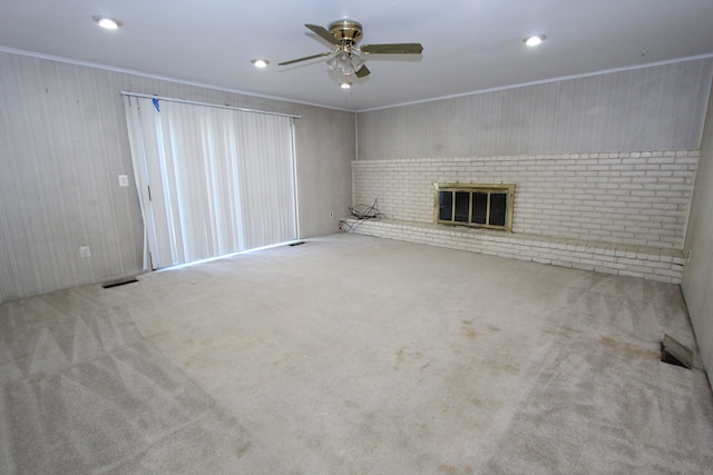 unfurnished living room featuring visible vents, ceiling fan, crown molding, carpet floors, and a brick fireplace