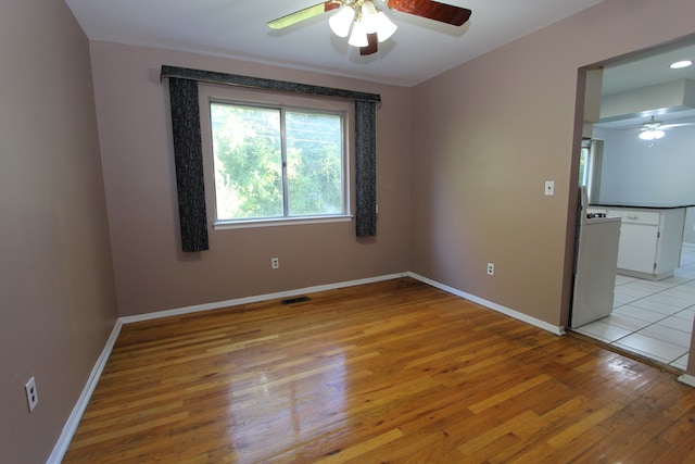 empty room featuring light wood-style floors, baseboards, visible vents, and a ceiling fan