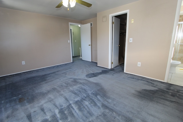 unfurnished bedroom with carpet floors, ensuite bath, a walk in closet, and a ceiling fan