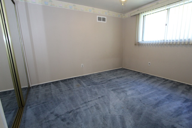 unfurnished room with visible vents and dark carpet