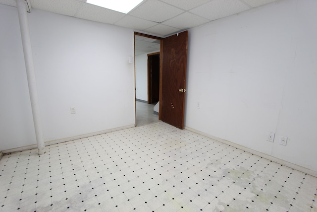 spare room featuring light floors and a drop ceiling