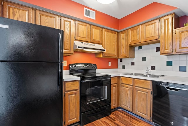 kitchen with under cabinet range hood, a sink, visible vents, light countertops, and black appliances