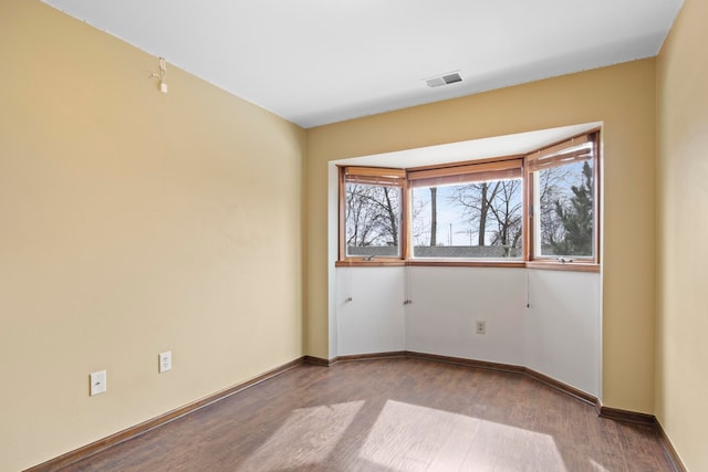 empty room with visible vents, baseboards, and wood finished floors