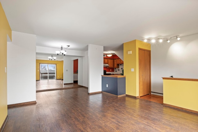 unfurnished living room with baseboards, dark wood finished floors, and an inviting chandelier