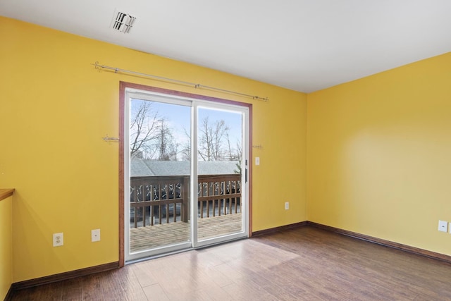 empty room with visible vents, baseboards, and wood finished floors