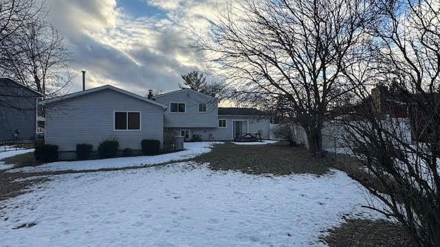 snow covered rear of property featuring central AC