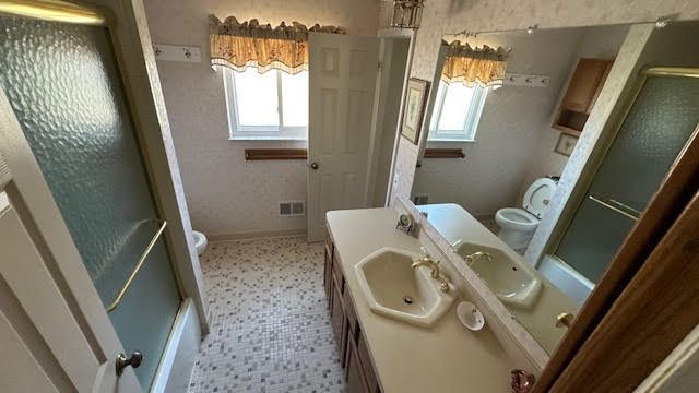 full bath with a shower with door, a healthy amount of sunlight, toilet, and vanity