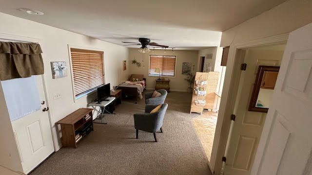 living room featuring a ceiling fan and carpet