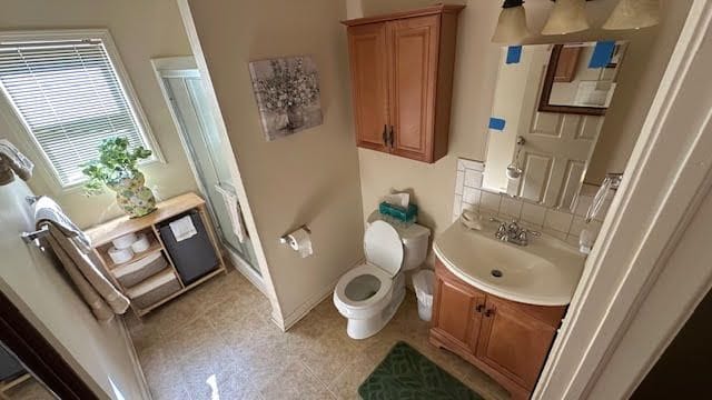 full bathroom featuring baseboards, vanity, a shower stall, and toilet