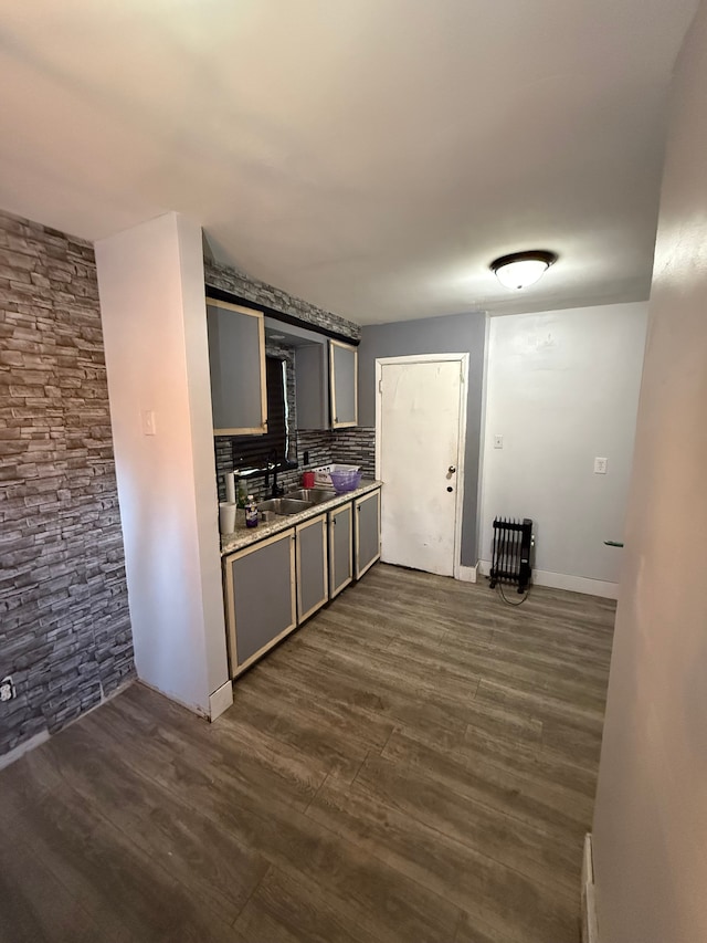 kitchen featuring decorative backsplash, dark wood-style flooring, gray cabinets, light countertops, and a sink