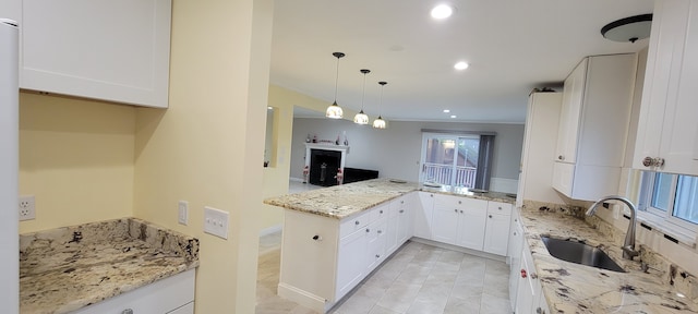 kitchen with white cabinets, a peninsula, light stone countertops, a sink, and recessed lighting