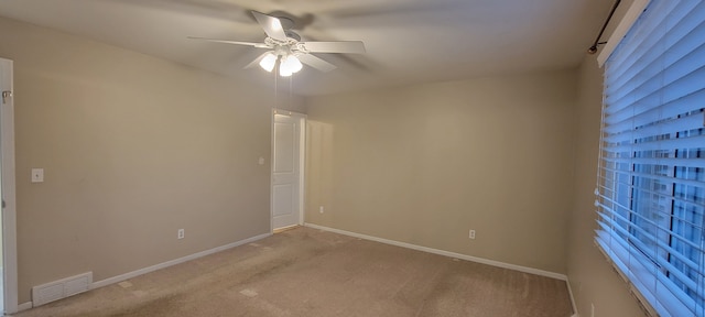 empty room featuring light carpet, baseboards, visible vents, and a ceiling fan