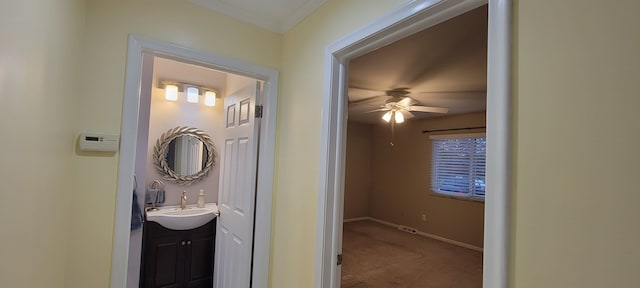 corridor featuring carpet, a sink, and baseboards